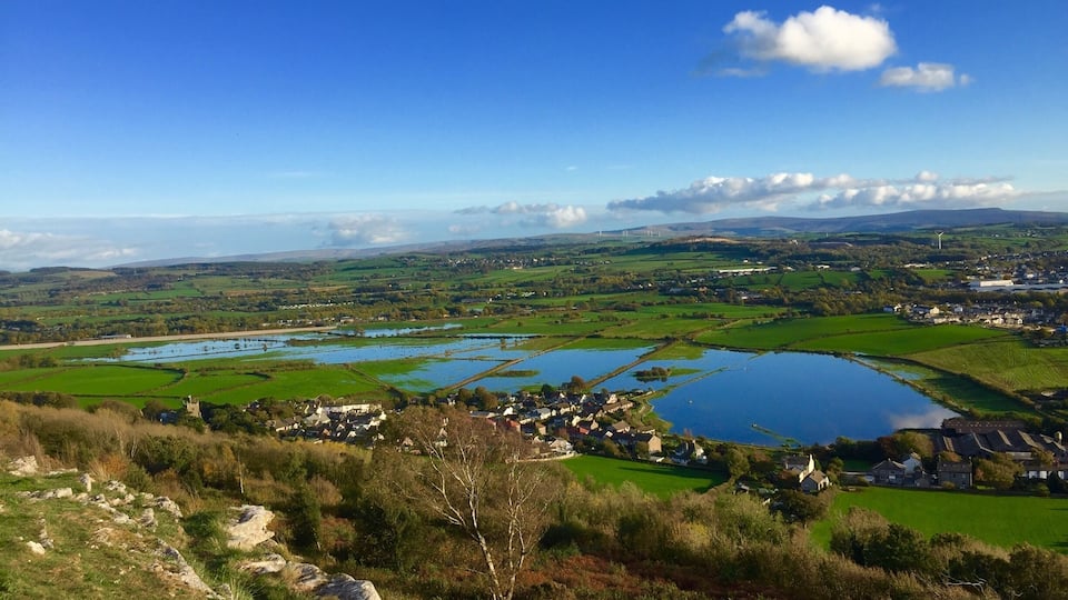 A rural landscape with a lake, fields, and a small village.