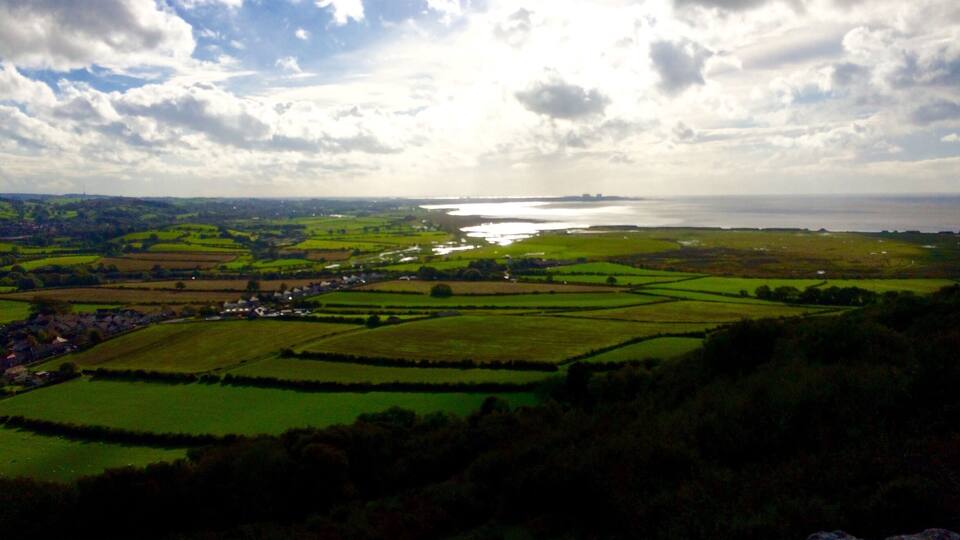A coastal landscape with fields, a small village, and a body of water.