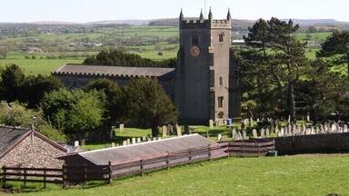 A church with a tall tower and a cemetery in the foreground.
