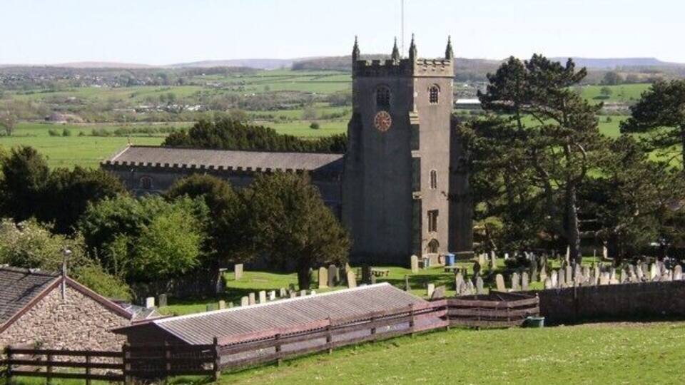 A church with a tall tower and a cemetery in the foreground.