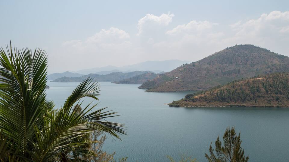 A calm lake surrounded by hills and palm trees.