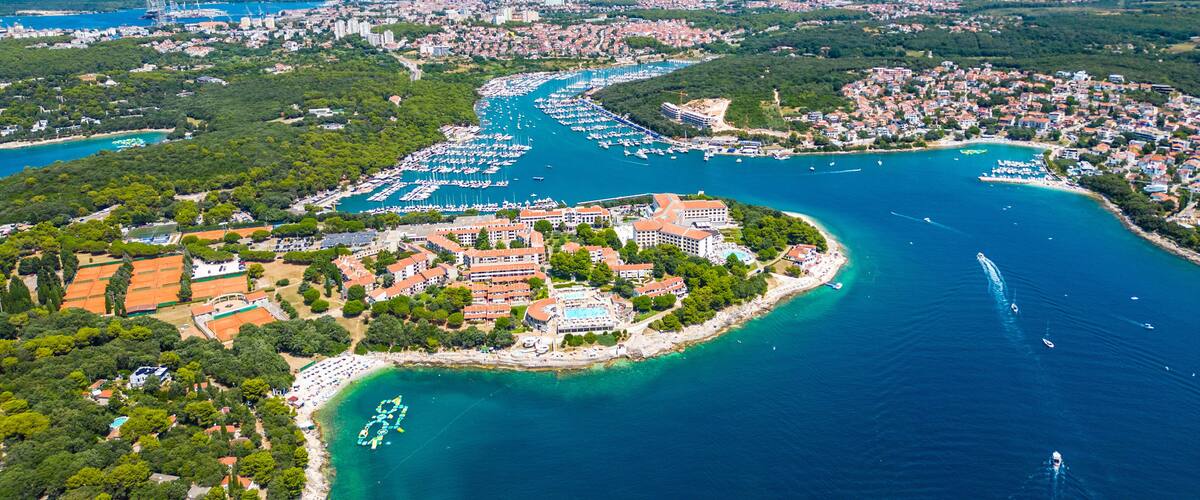 An aerial view of a coastal city with a marina, residential areas, and a beach.