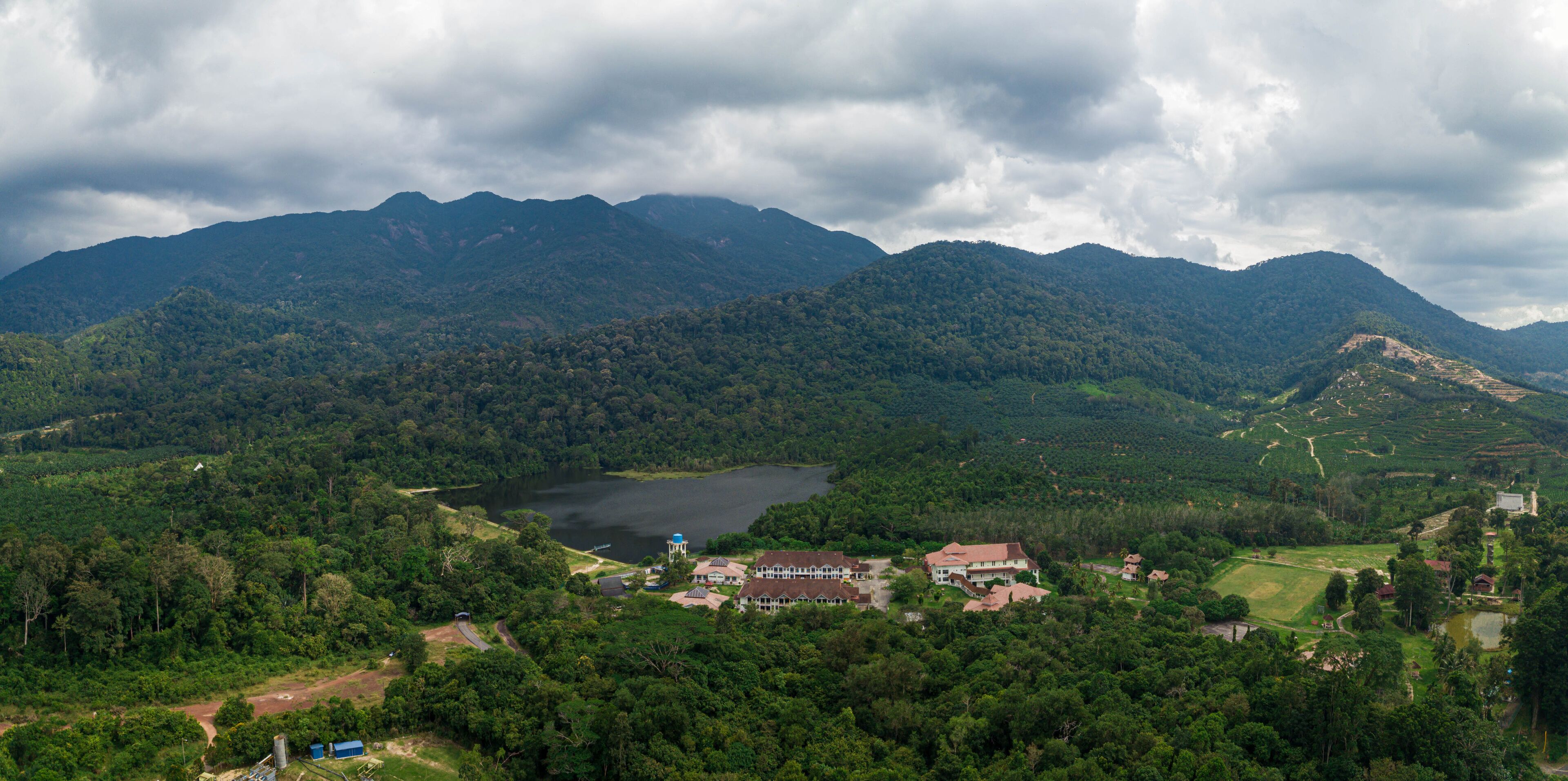 A mountainous landscape with a lake, a large house, and a tower.