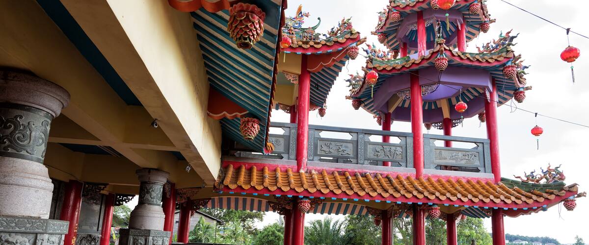 A traditional multi-tiered pagoda with ornate red and yellow roofs, intricate carvings, and red pillars.