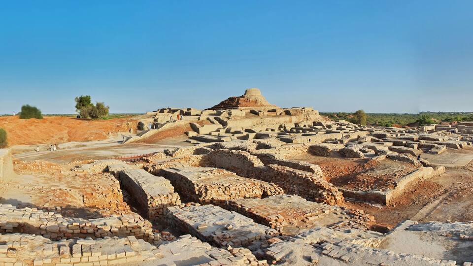Ancient ruins with a large mound and scattered brick structures.