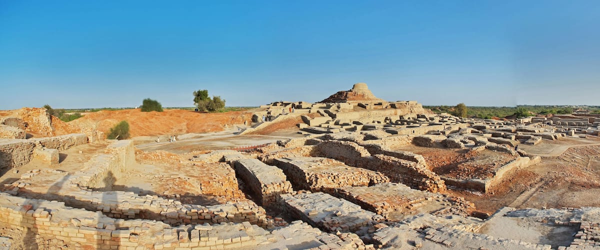 Ancient ruins with a large mound and scattered brick structures.