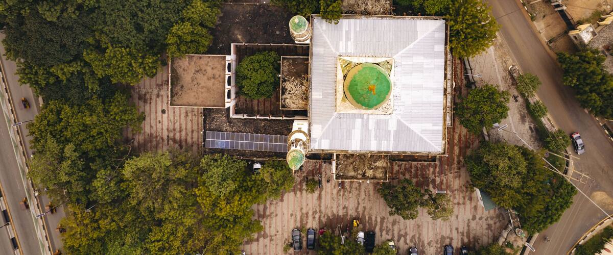 An aerial view of a building surrounded by dense trees and a road.