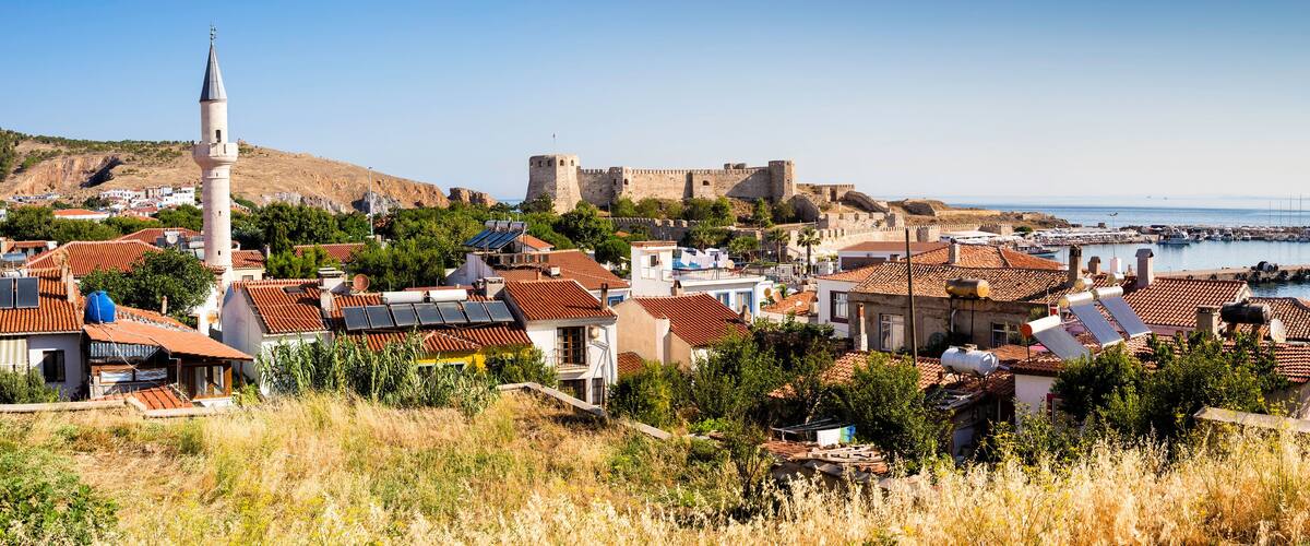 A coastal town with historic fortifications, a mosque, and a marina.