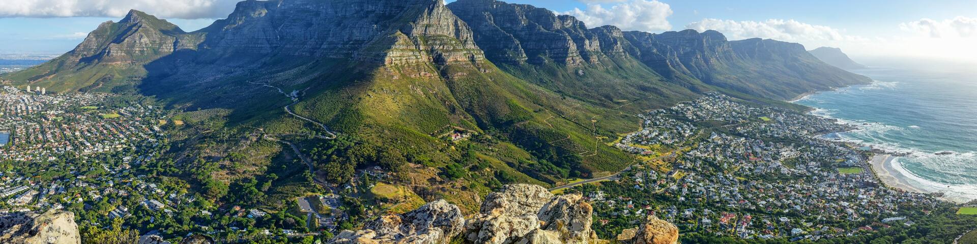 A mountainous landscape with a town at the base, overlooking the ocean.