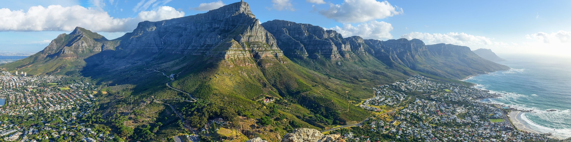 A mountainous landscape with a town at the base, overlooking the ocean.