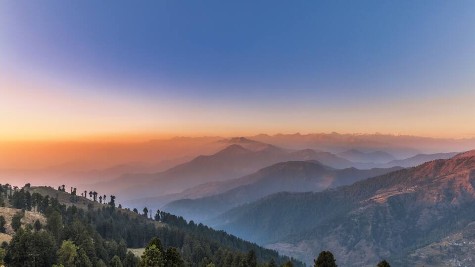 A mountainous landscape with a clear sky during sunset.