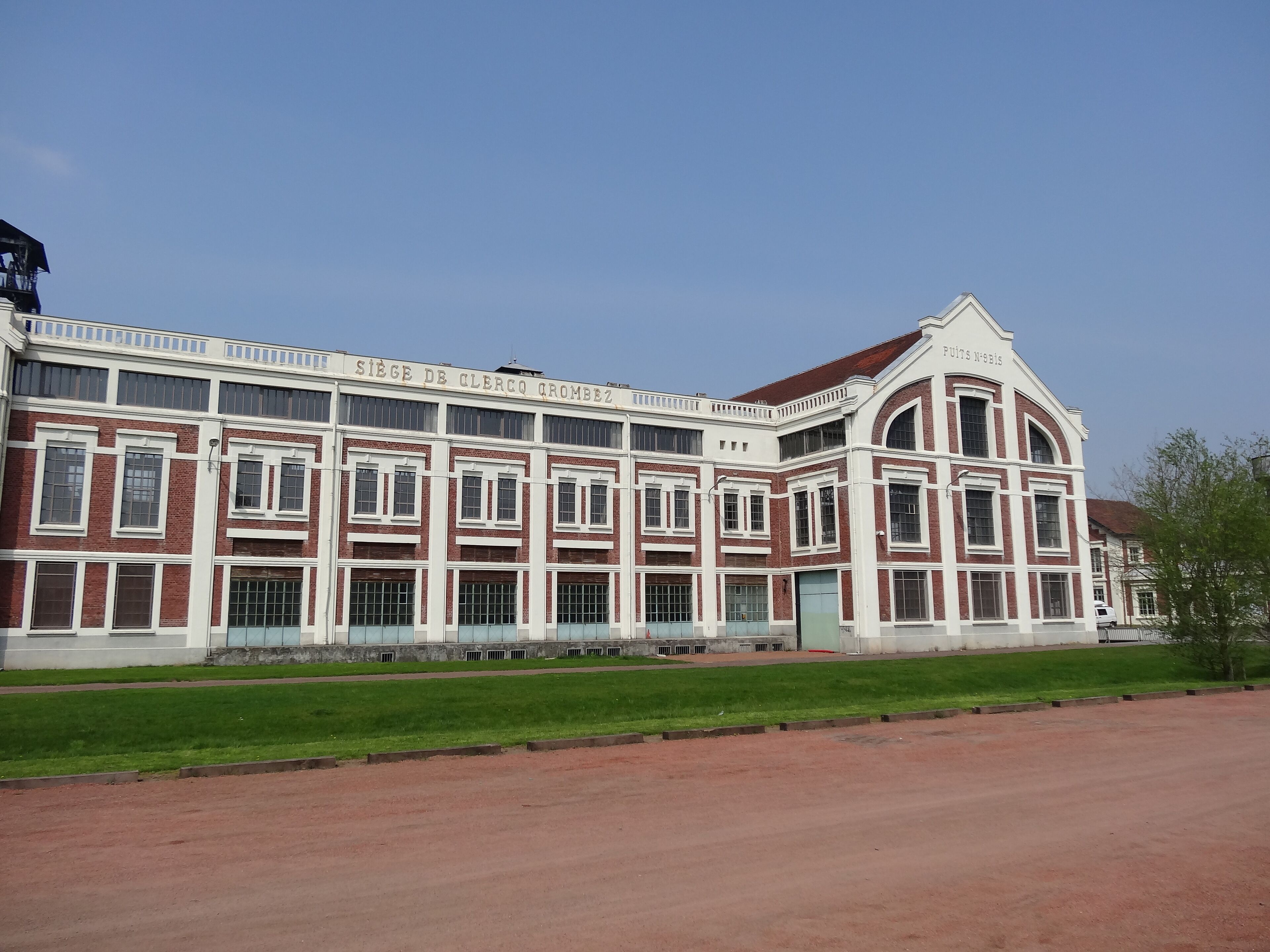 A large, historic building with red brick and white trim, featuring multiple windows and a prominent arched entrance.