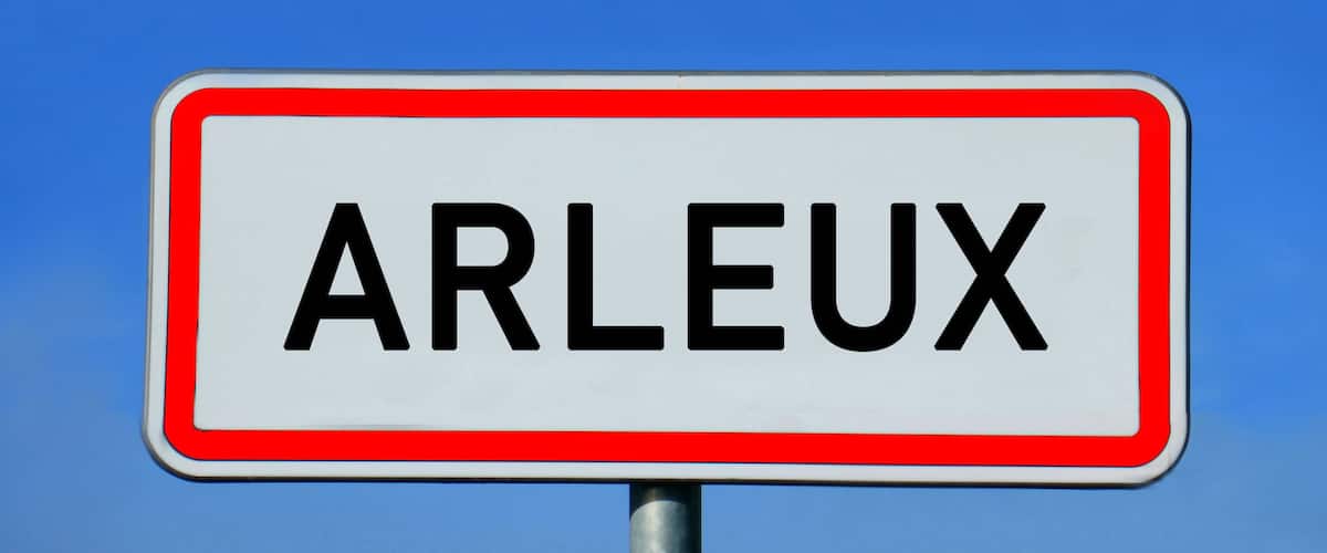 A road sign with the word "ARLEUX" against a blue sky.