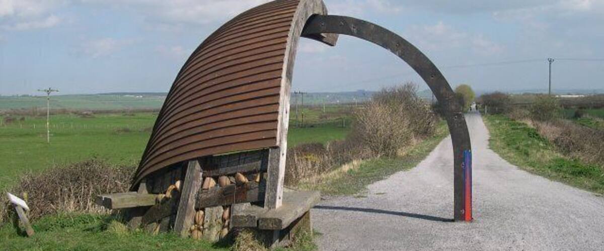 A rural road with a unique metal archway structure.