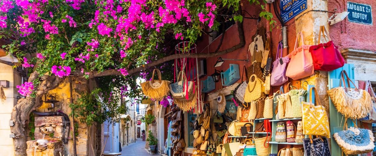 Una calle estrecha flanqueada por tiendas que ofrecen coloridos bolsos y textiles.