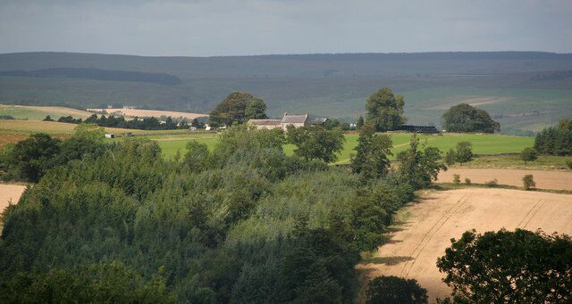 A rural landscape with a farm, rolling hills, and a clear sky.