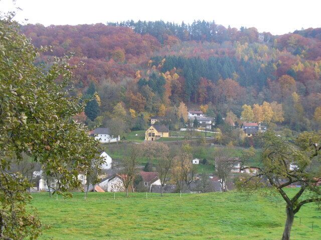 A rural landscape with autumn-colored trees, a small village, and a prominent yellow building.