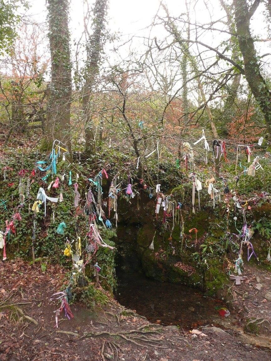 This is on a local bridalway that leads to the beach.  It's used as a wishing well by the locals, I'm not sure if it has any genuine history as a wishing well and really it's more of a wishing tiny stream, but it looks kind of cool with its many different ribbons and bows tied to the tree!