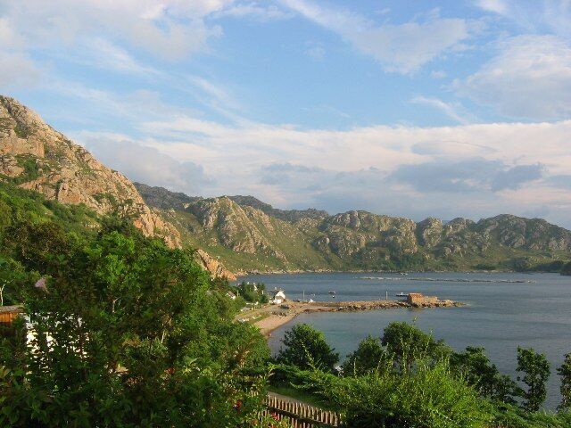A coastal landscape with mountains, a beach, and a small settlement.