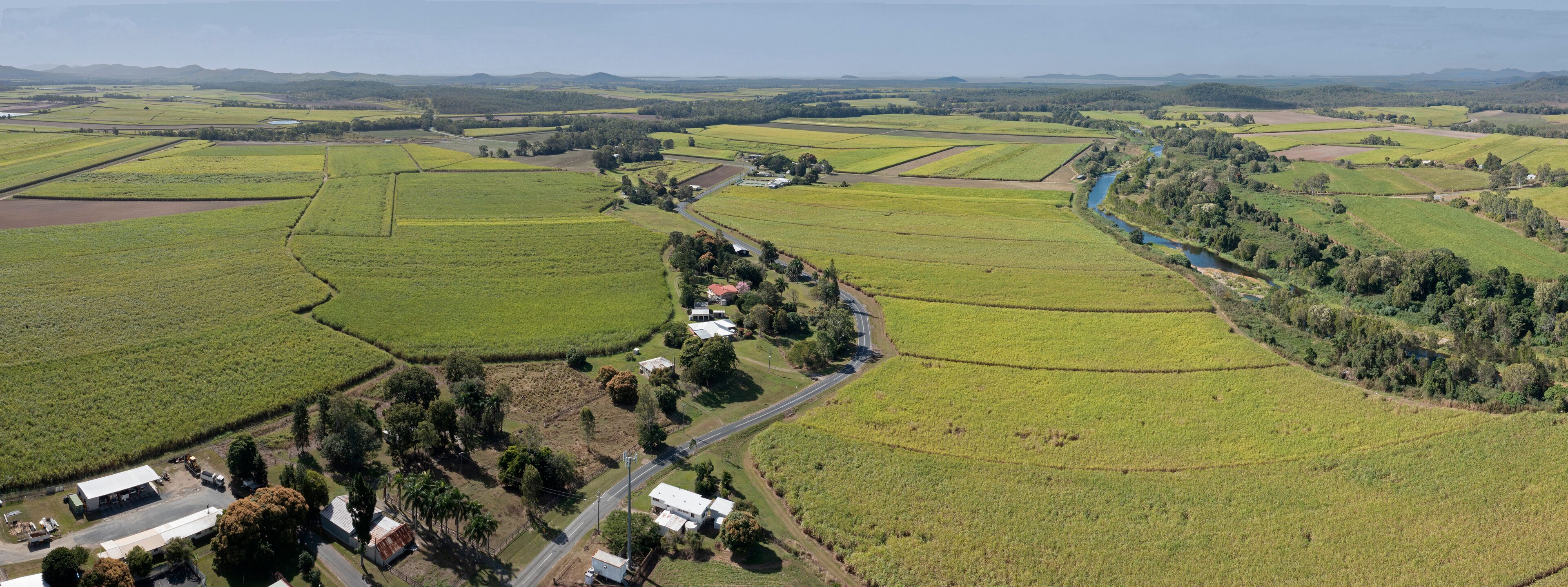 An aerial view of a rural landscape with fields, a river, and scattered buildings.