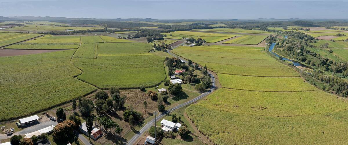 An aerial view of a rural landscape with fields, a river, and scattered buildings.