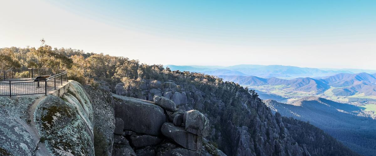 A rocky cliff with a viewing platform overlooking a valley.