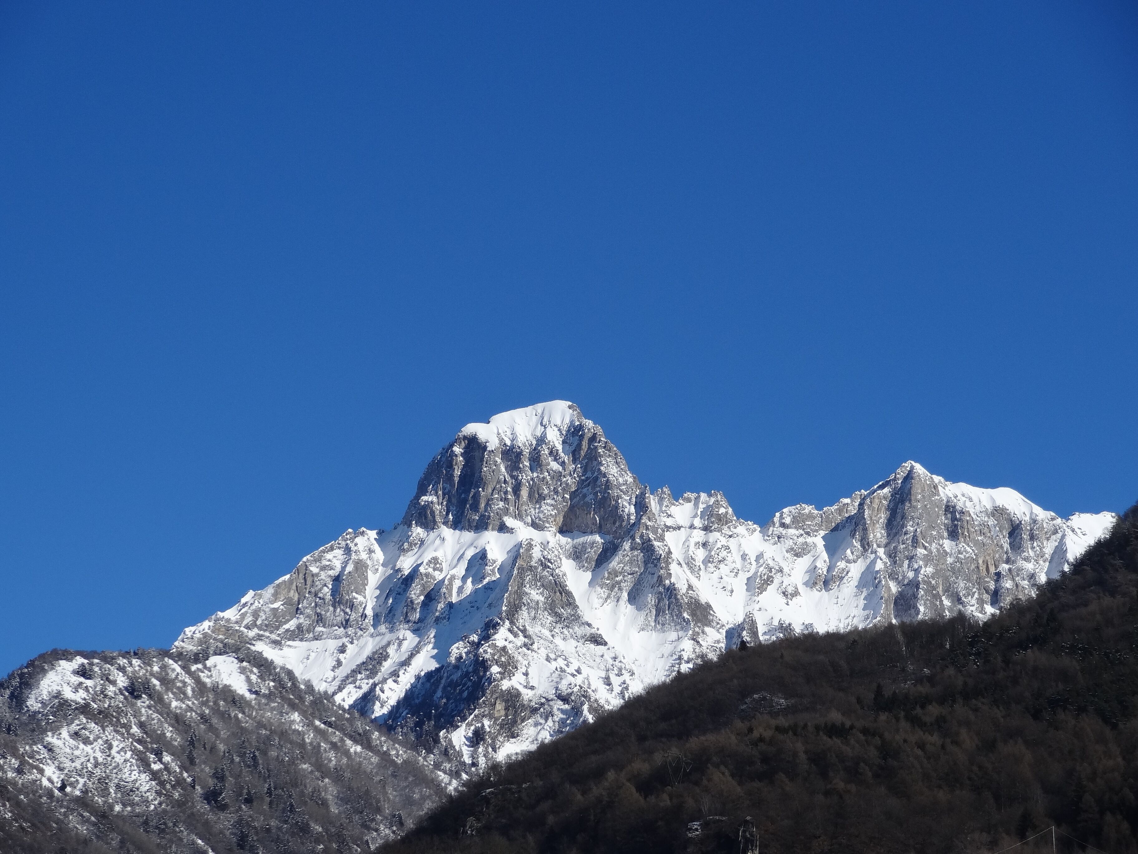 A snow-covered mountain peak with a clear blue sky.