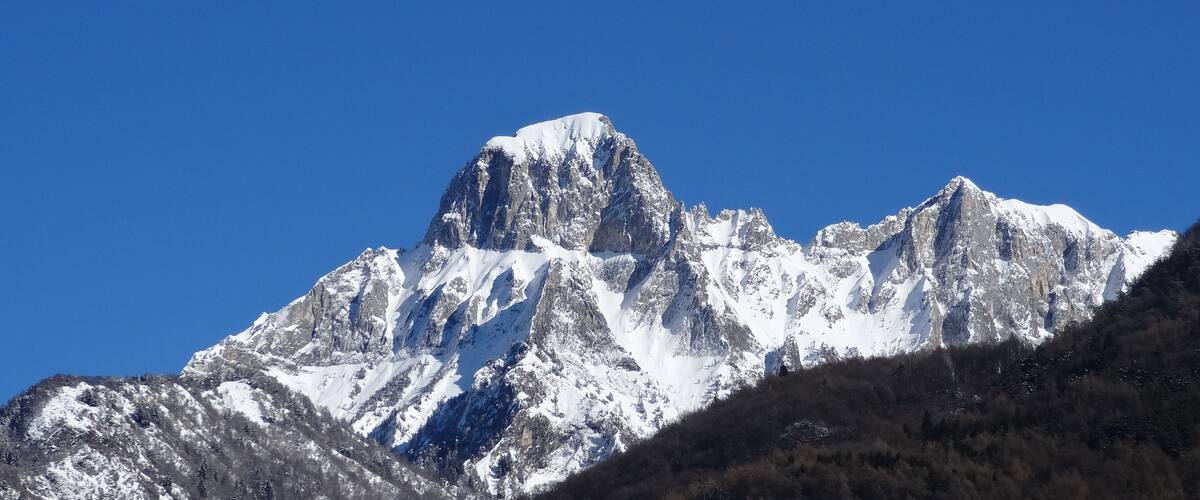 A snow-covered mountain peak with a clear blue sky.