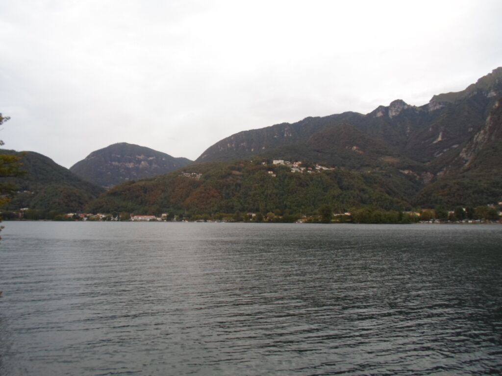 A lake surrounded by mountains with a few buildings on the hills.