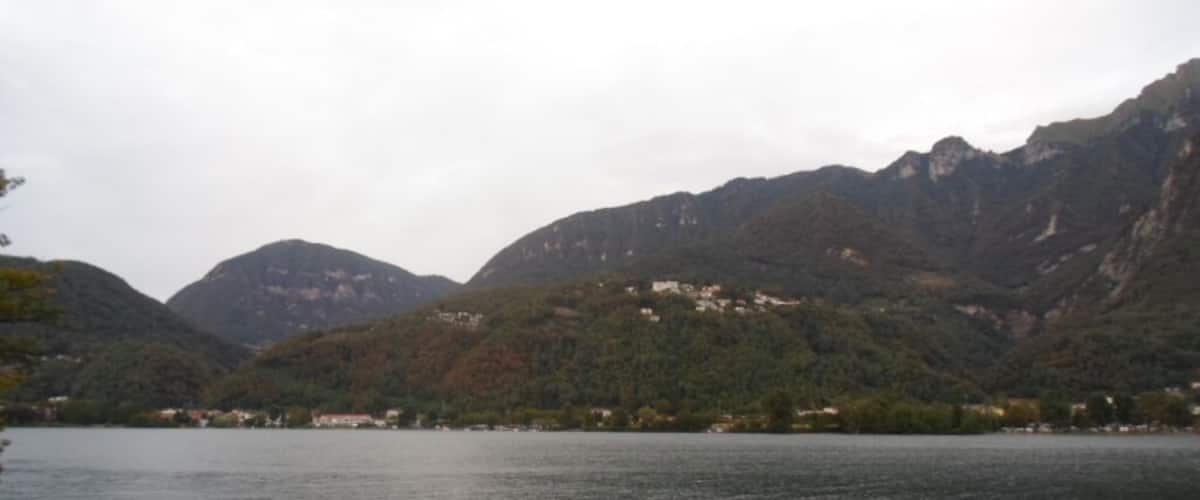 A lake surrounded by mountains with a few buildings on the hills.