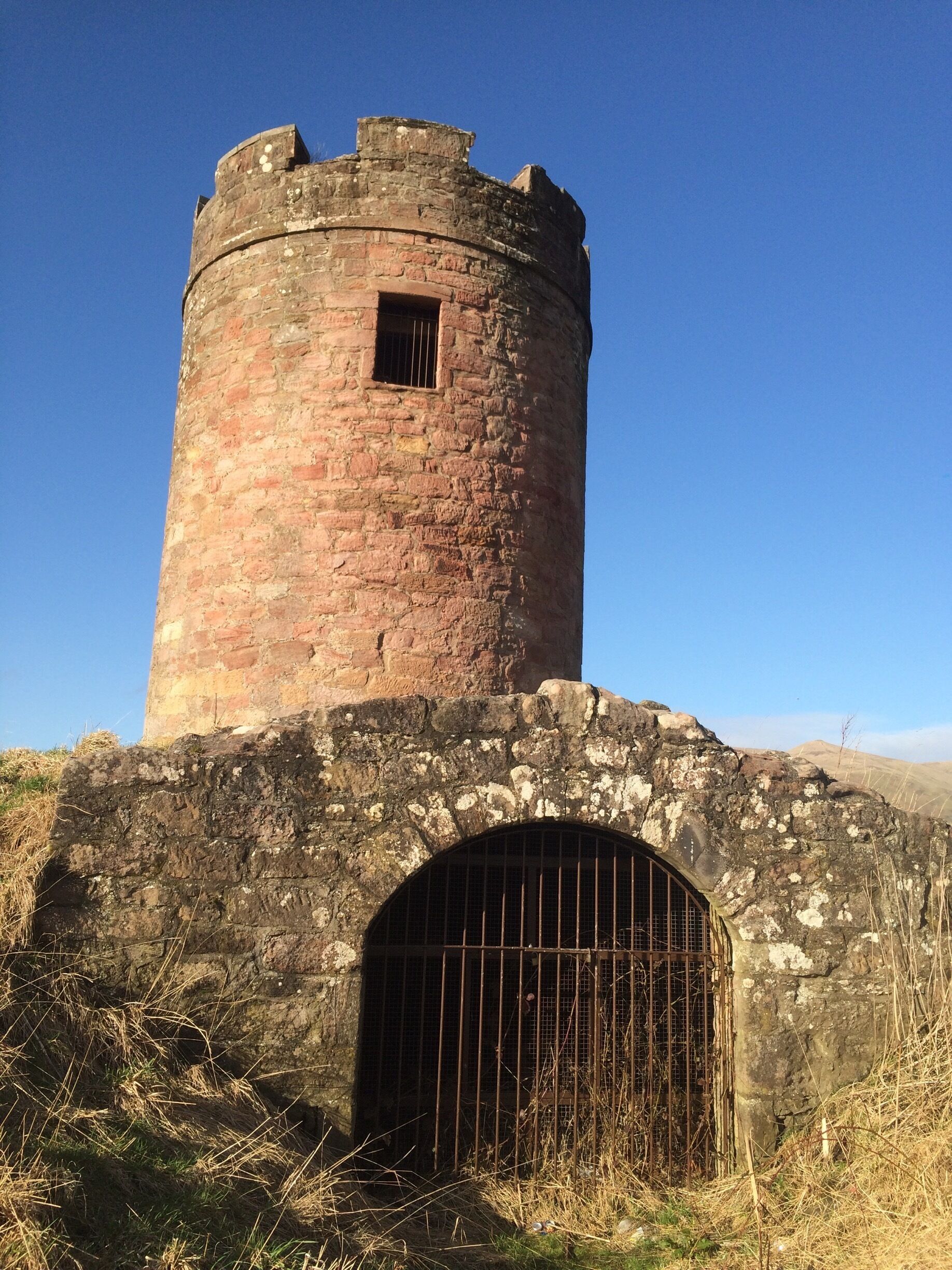 A circular stone tower with a barred entrance and a small window.