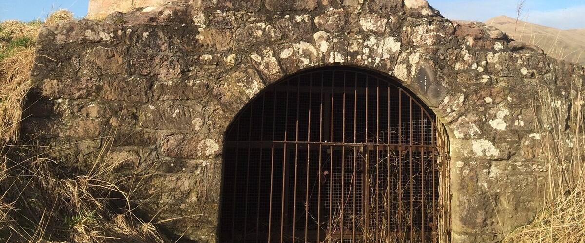 A circular stone tower with a barred entrance and a small window.