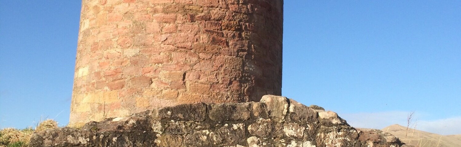 A circular stone tower with a barred entrance and a small window.