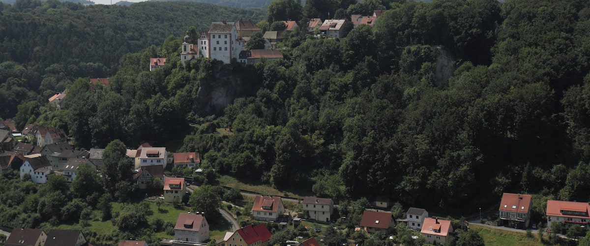 A village nestled in a valley with a prominent castle-like building on a hill.