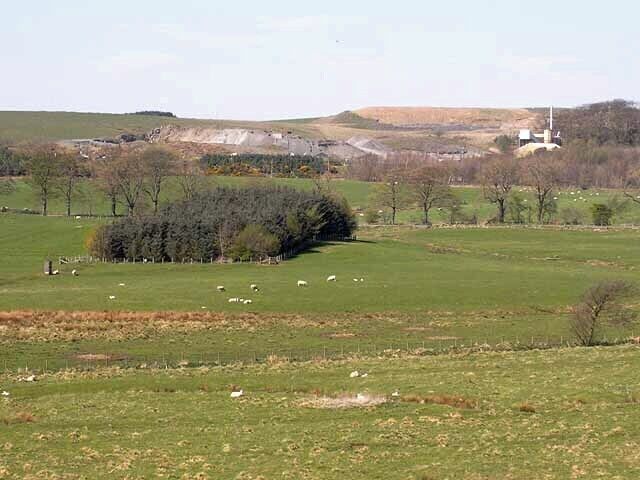Divethill Quarry Whinstone quarry near Little Bavington. The B6342 runs along the tree line in the middle distance.