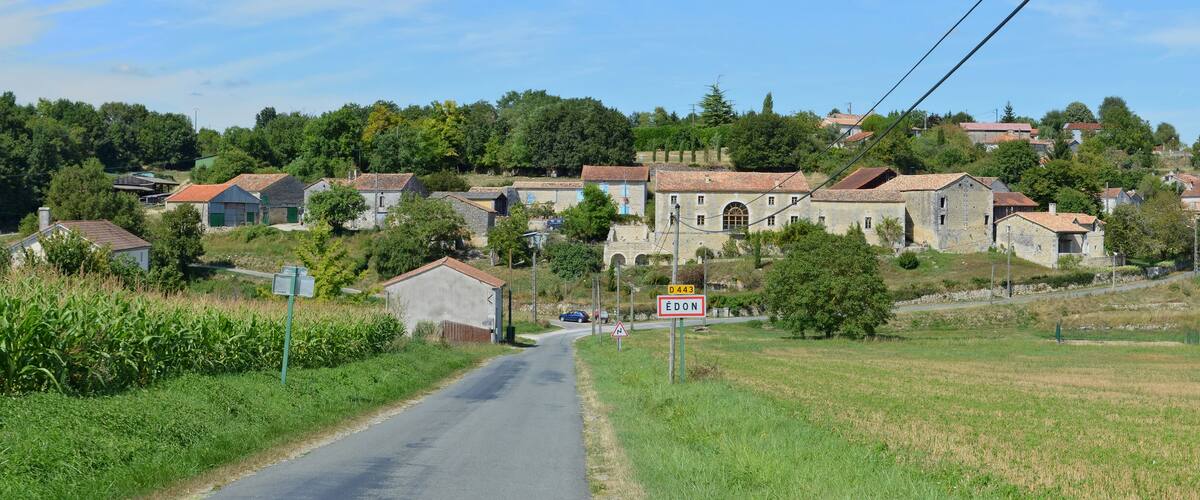 A rural village with stone houses, a winding road, and a church tower.