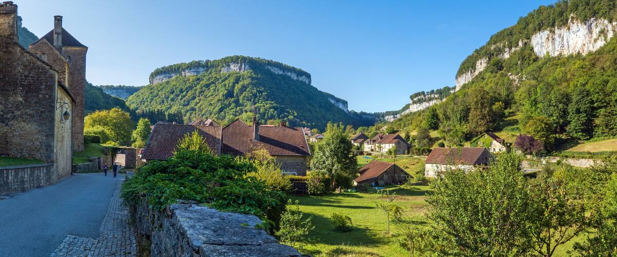 A village with stone buildings, a church, and a mountain in the background.