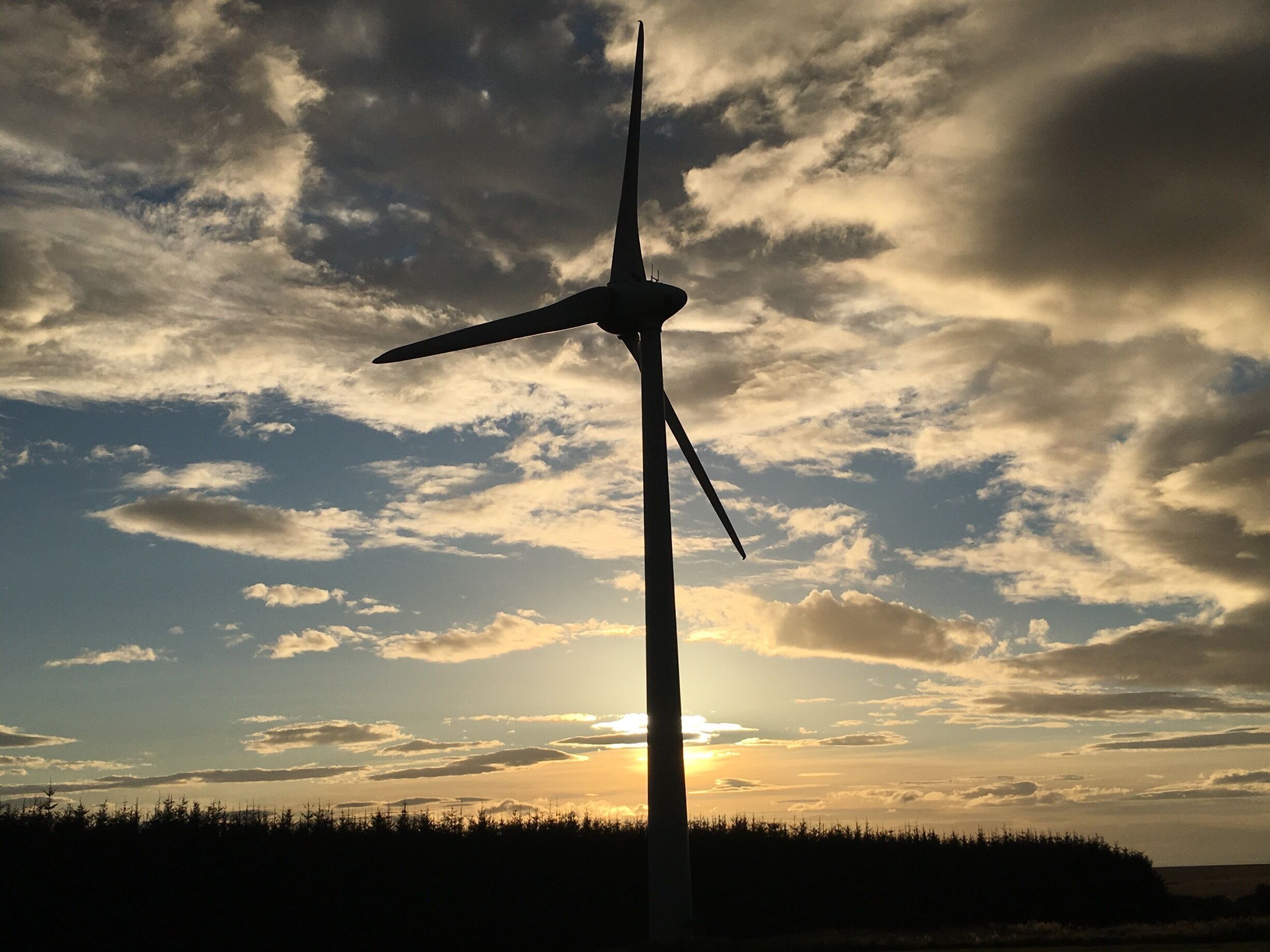 A wind turbine silhouetted against a sunset sky.
