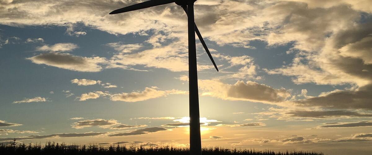 A wind turbine silhouetted against a sunset sky.