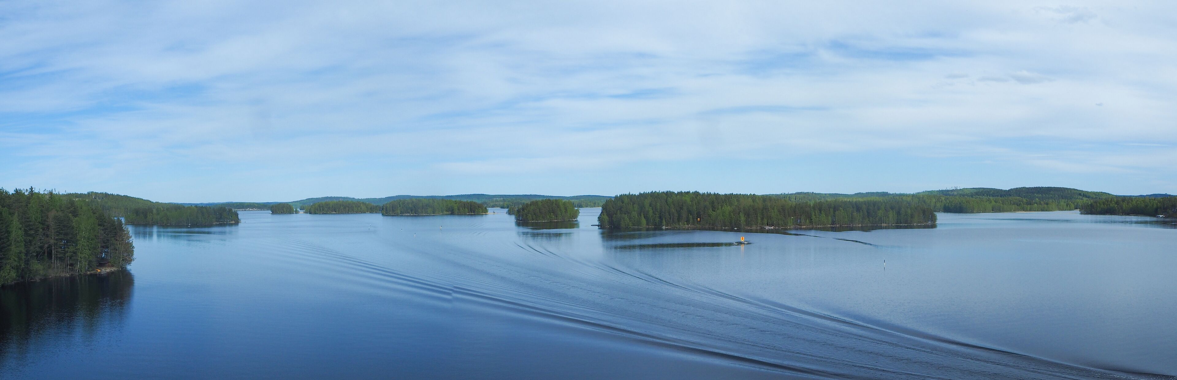 A calm lake surrounded by dense forests and small islands.