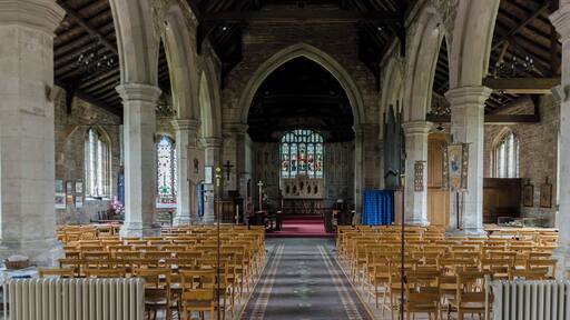 Interior. Note the painted chancel. The church was built around 1434, with restoration in the 1870s. It consists of a nave with aisles, western tower, chancel, and north porch. Some parts of the demolished Bardney abbey were used in the church. The tower dates from the late 15th century and has battlements topped with eight pinnacles. It has six bells. The north aisle of 5 bays is from the mid-to late 15th century, the south aisle is of the same date. The piers are octagonal. There is a 17th-century north porch with benches. The chancel is made of brick; Some say the same bricks used to build Tattershall Castle. Inside are murals of 1935 by A. Willets depicting Saints, and there are carved angels in the roof timbers. There is a 19th-century reredos and a 15th century piscina in the south wall. There is also a 14th century figure originally from Bardney Abbey. At the west end of the nave is an incised slab to Abbot Richard Horncastle, died 1508, and three painted wooden panels recording charitable donations. The font and choir stalls are 20th century. There are several architectural fragments from Bardney Abbey on display. The two manual organ is by Cousans. Restoration work was carried out in the 1870s at a cost of some £2500, during which the west end of the north aisle was formed into a baptistery. Further restoration was done in the late 1990s.