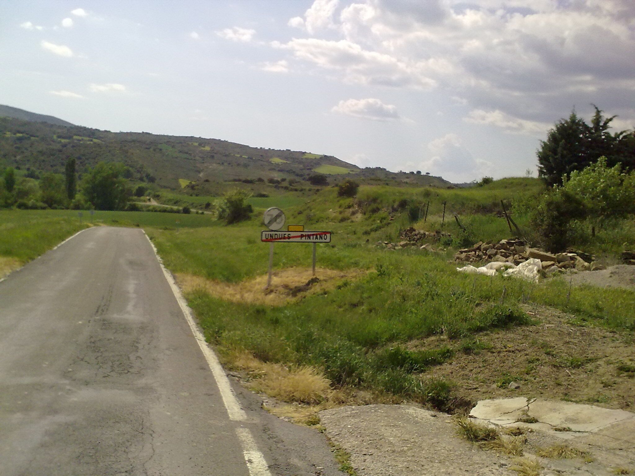 A rural road with a sign indicating 'UNDUE PINTANO' and a no parking sign.