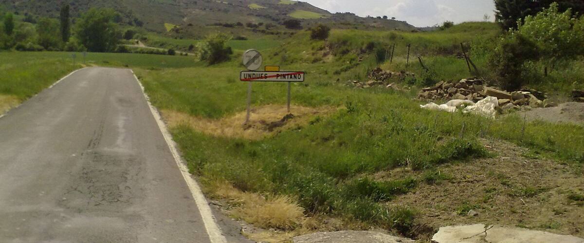 A rural road with a sign indicating 'UNDUE PINTANO' and a no parking sign.