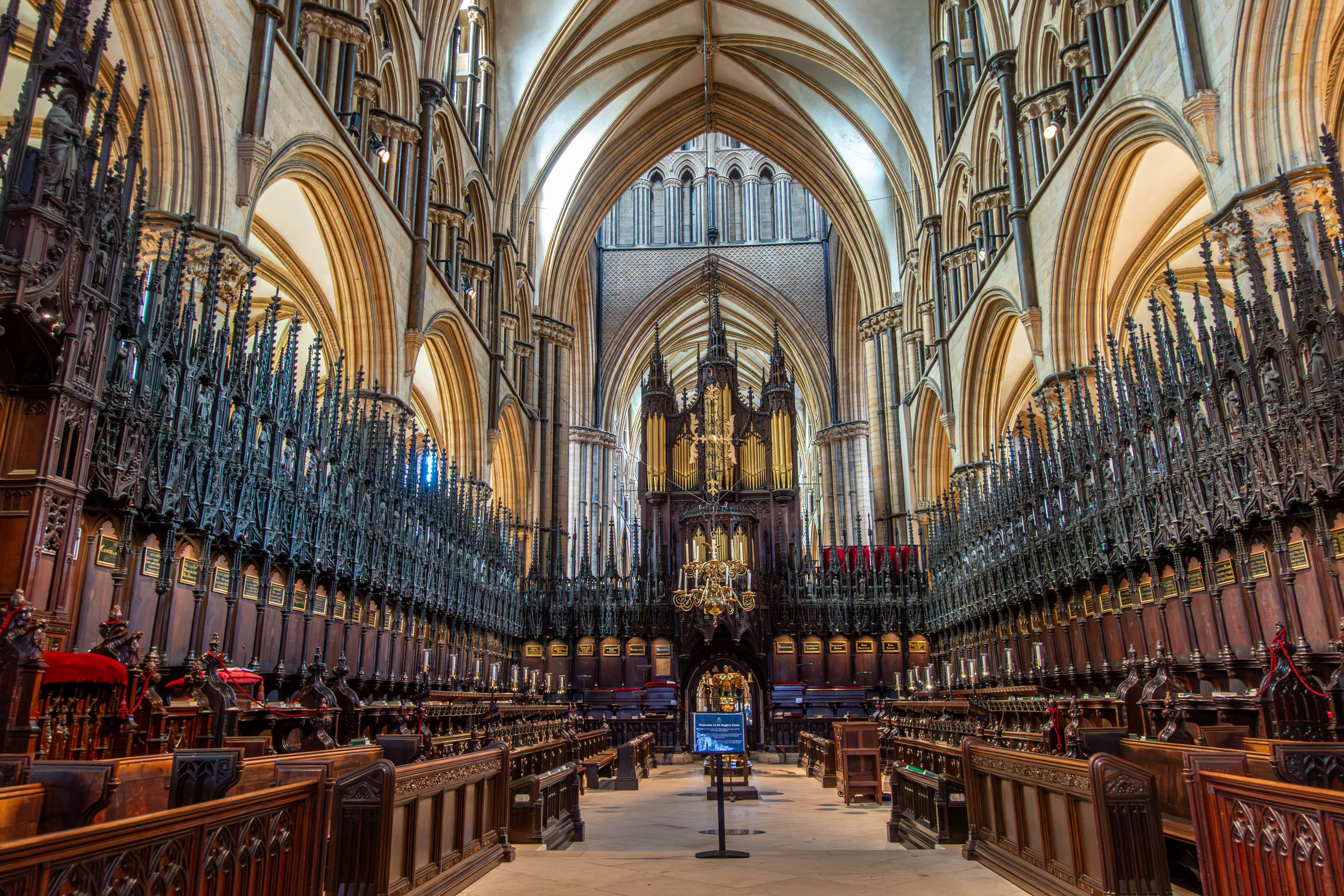Un interior de catedral majestuoso con arquitectura gótica, incluyendo arcos apuntados, bóvedas de crucería y una extensa zona del coro.