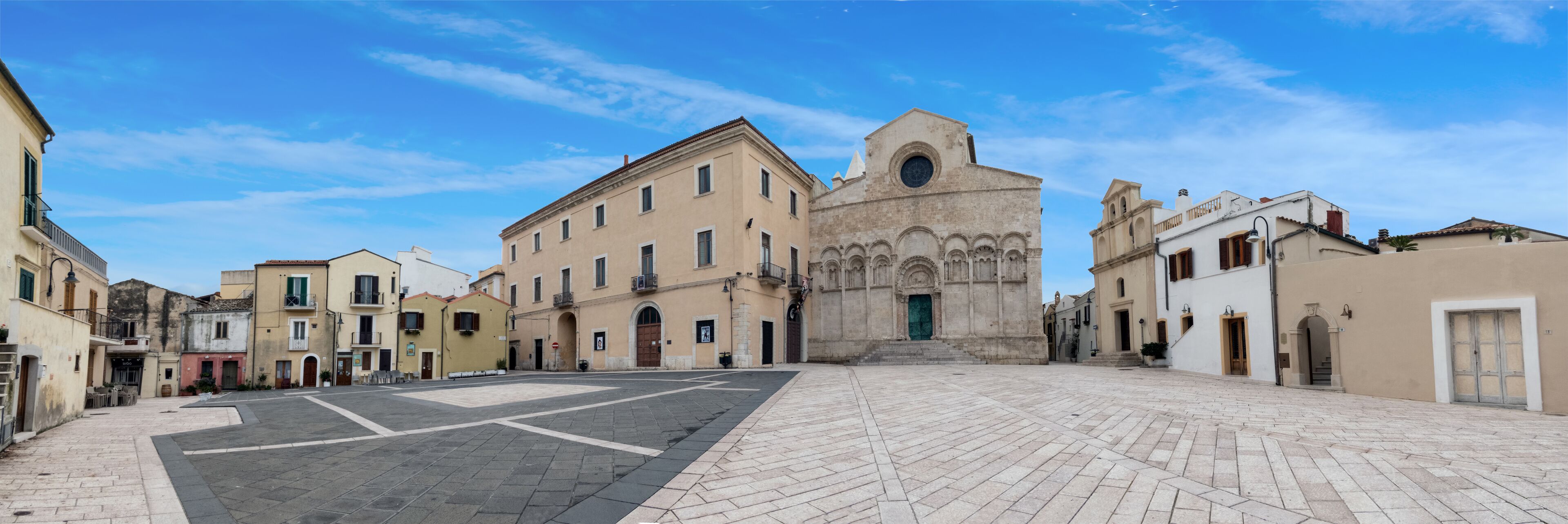 A historic square with a prominent church featuring a circular window and a bell tower.