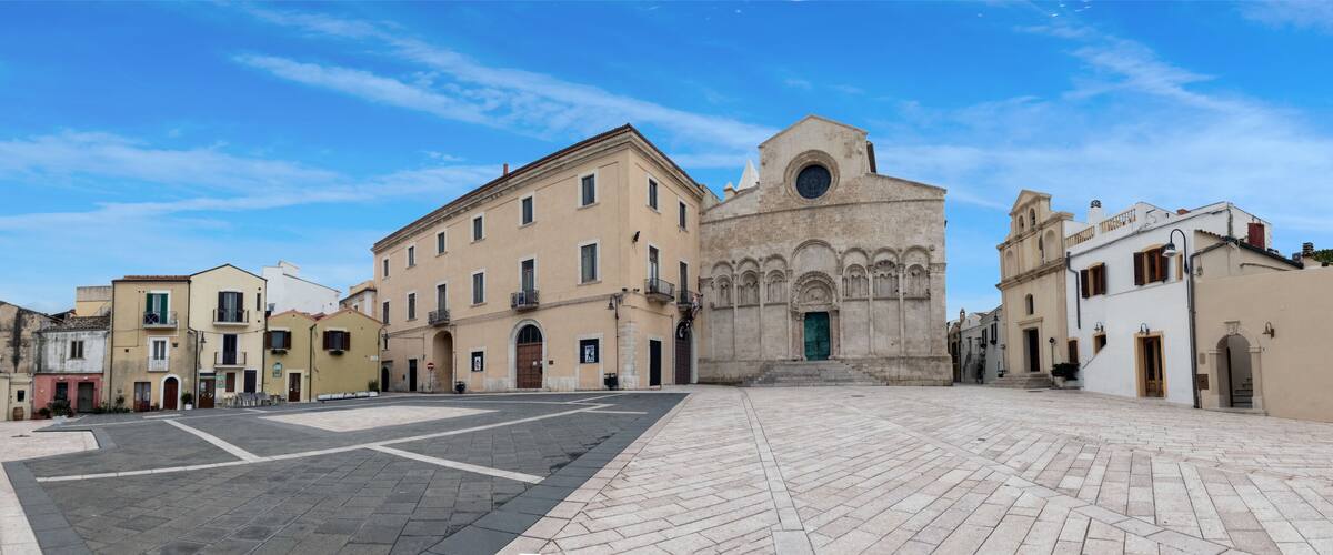 A historic square with a prominent church featuring a circular window and a bell tower.
