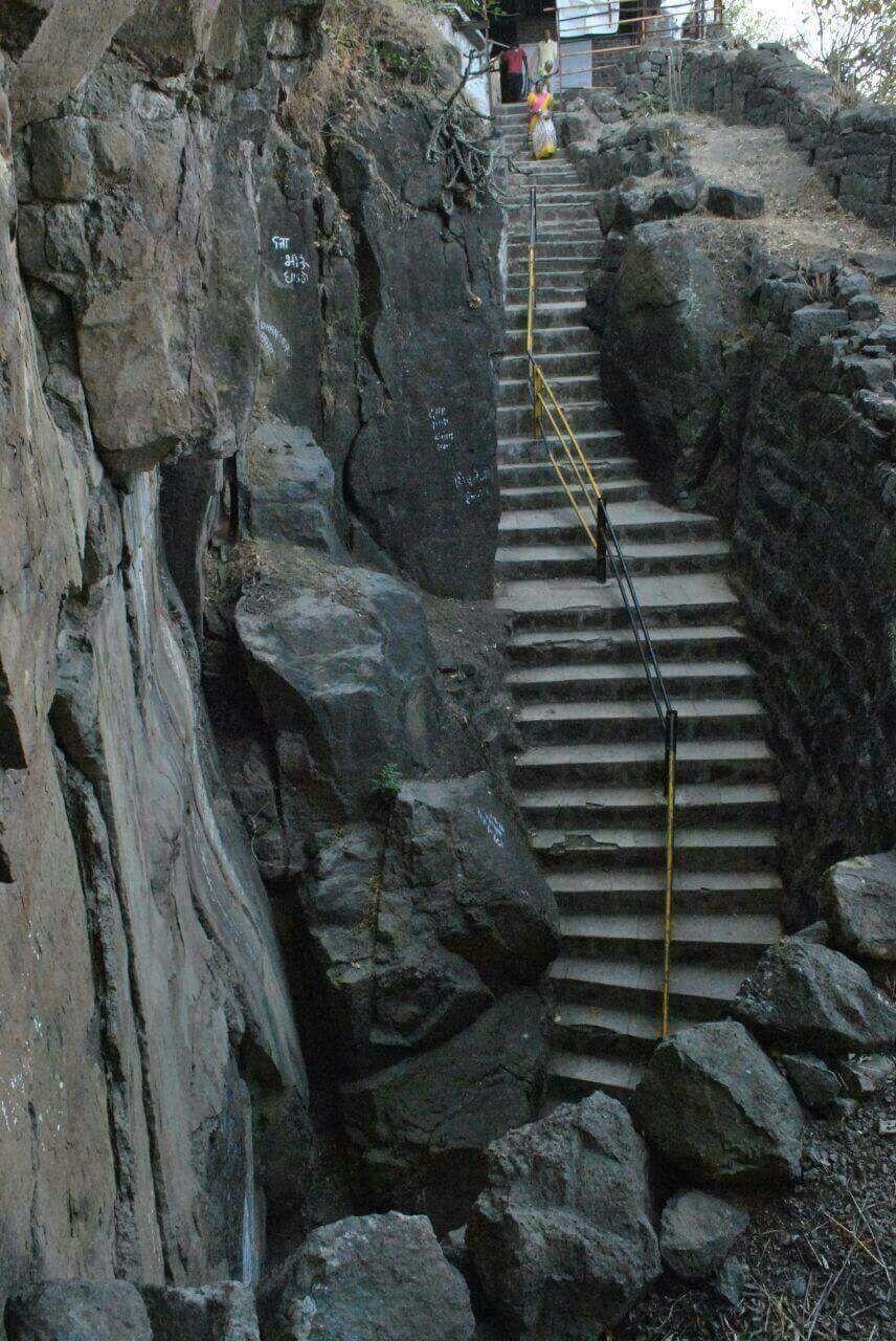 A rocky staircase leading up a mountain with a yellow safety line.