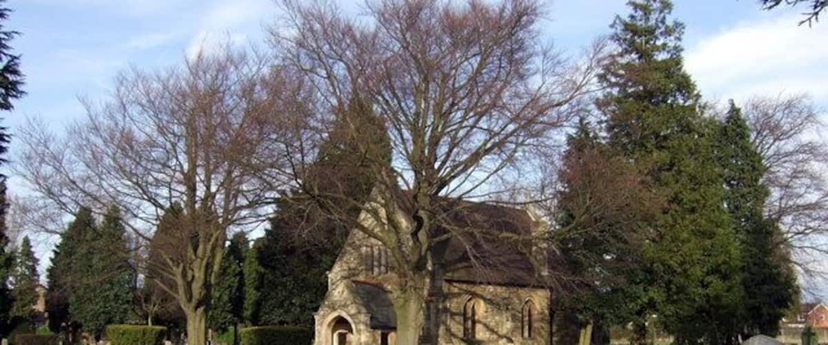A cemetery with a church, gravestones, and trees.