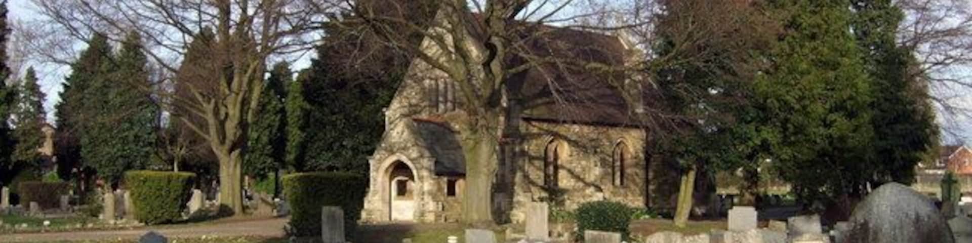 A cemetery with a church, gravestones, and trees.