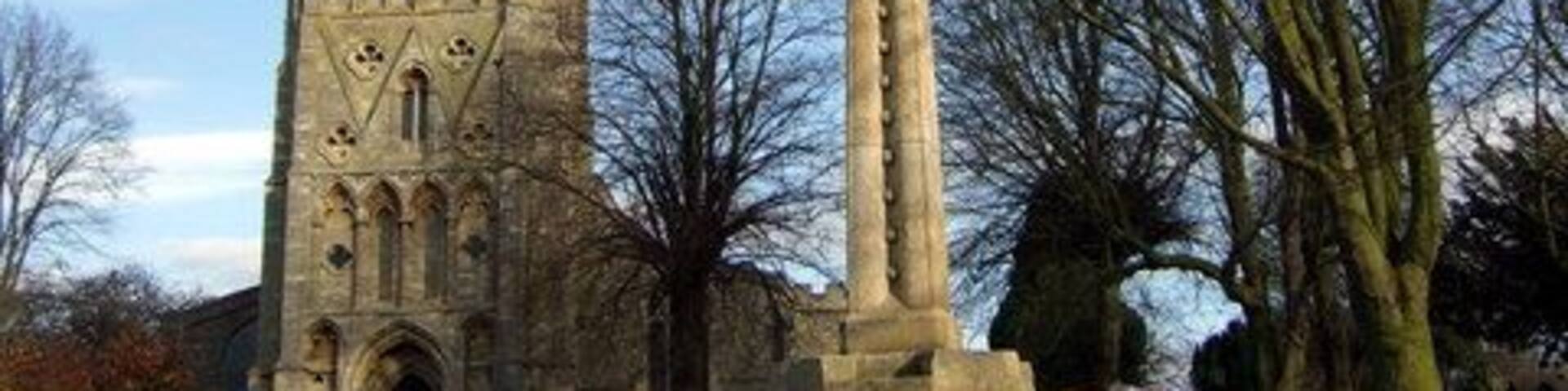 Raunds, Northamptonshire: war memorial (foreground) and St Peter's parish church (background). The memorial was originally erected in the Market Square in memory of servicemen killed in the First World War. It was moved to its present site in 1950 when the names of the Second World War dead were added.